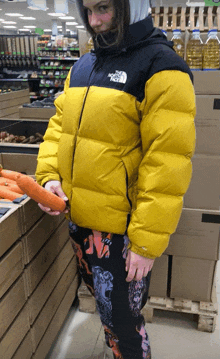a person wearing a yellow north face jacket holds a carrot