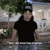 a man standing in front of a house says " and i still know how to kefir "
