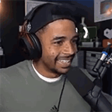 a man wearing headphones is sitting in front of a microphone and smiling .