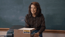 a teddy bear is sitting at a desk in a classroom with a book open .