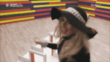 a woman wearing a black hat is dancing in front of a wall that says teakoz live