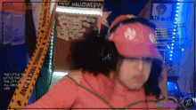 a woman wearing a pink hat and headphones is standing in front of a halloween sign