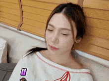 a woman with her eyes closed is wearing a white shirt with a banana on the front