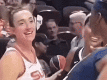 a woman in a basketball jersey with the letter s on it is talking to a man .
