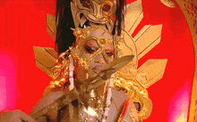 a woman in a gold costume is holding a sword in front of her face