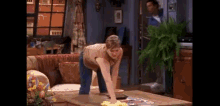a woman is cleaning a coffee table in a living room with a yellow cloth .