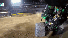 a monster truck is driving on a dirt track with monster energy written on the side