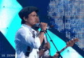 a man sings into a microphone while another man plays a guitar in front of a screen that says 16 denmark