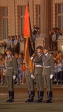 a group of soldiers stand in front of a crowd holding flags one of which says " reichstag "