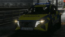 a yellow and blue garda car is parked on the side of the road