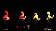 a group of jugglers are performing on a stage with a nbc logo behind them
