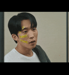 a man with yellow bandages on his face looks at the camera