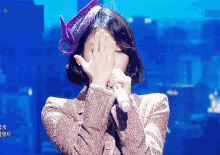 a woman wearing a purple hat is covering her face with her hands