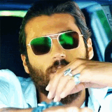 a man with a beard wears sunglasses and a ring on his finger