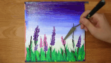 a person is painting purple and pink flowers on a purple background