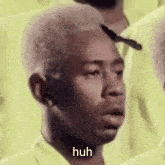 a man in a yellow shirt is making a funny face and says huh .