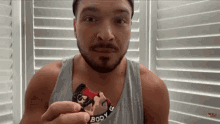 a man with a beard is holding a body g bar in his hand .