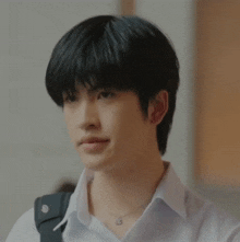 a young man wearing a white shirt and a black backpack