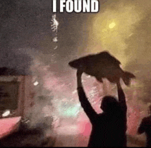 a man is holding a large fish in the air in front of a building .