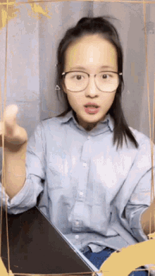 a woman wearing glasses and a blue shirt is making a funny face