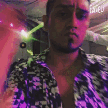 a man with a beard is taking a selfie in a room with purple lights behind him .