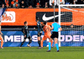 soccer players on a field with a nike ad in the background