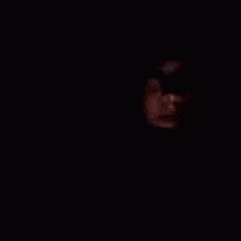 a close up of a person 's face in the dark with a hood on .