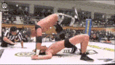a man is doing a handstand in a wrestling ring while a referee watches .