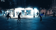a group of people are skateboarding on a street at night