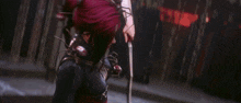 a woman in a red dress is holding a sword in a dark room