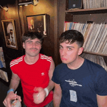 a man in a red adidas shirt stands next to another man