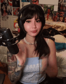 a girl wearing headphones and a pearl necklace is standing in front of a microphone .