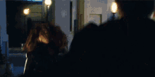 a man and a woman are standing next to each other in a dark room . the woman is wearing a black leather jacket .