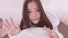 a young woman is laying in bed with her hands outstretched and smiling .