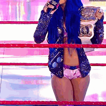 a woman with blue hair is standing in a wrestling ring holding a world heavyweight championship belt .