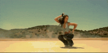 a woman is squatting down in the desert