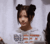 a girl is wearing a dirty sweatshirt and has two buns in her hair