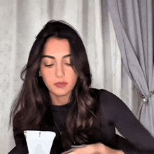 a woman is sitting in front of a white curtain with her eyes closed and a watermark that says zeudgifs