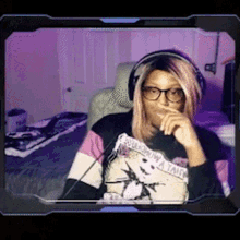 a woman wearing headphones and glasses is sitting in front of a computer monitor