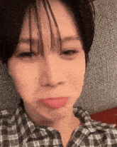 a woman in a plaid shirt is making a face