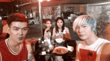 a group of people are sitting at a table with plates of food and drinks .