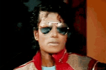 a close up of a man wearing sunglasses and a red jacket .