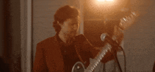 a man is playing a guitar and singing into a microphone .