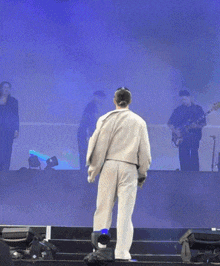 a man in white pants is standing on a stage in front of a blue backdrop