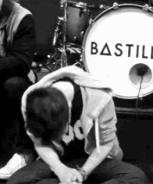 a man is kneeling down in front of a drum with the word bastille written on it .