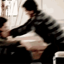 a man in a striped sweater is holding another man 's arm in a blurry photo .