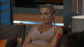 a woman in a purple tank top sits in a chair with her hands on her hips