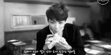 a black and white photo of a young man eating a sandwich in a classroom .