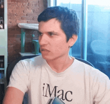 a man wearing a white t-shirt that says imac on it