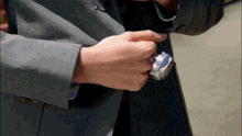 a person in a suit is holding a watch in their pocket